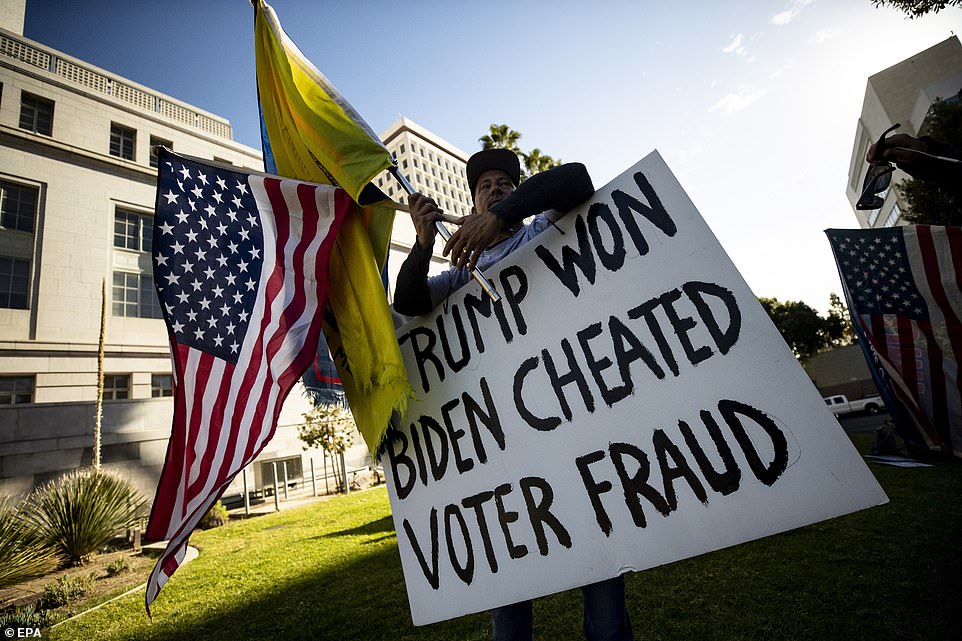 LA: A Trump supporter holds a placard reading 'Trump Won Biden Cheated Voter Fraud' during a demonstration outside City Hall