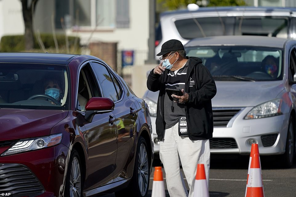 Pictured, a healthcare worker directs vehicles to a COVID-19 test area at a drive-thru testing center in Phoenix on Wednesday as Arizona reported a triple-digit number of COVID-19 deaths for the second day in a row along with more than 7,200 cases