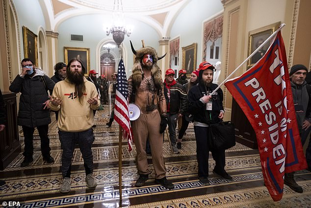 Supporters of US President Donald J. Trump stand by the door to the Senate chambers after they breached the US Capitol security yesterday