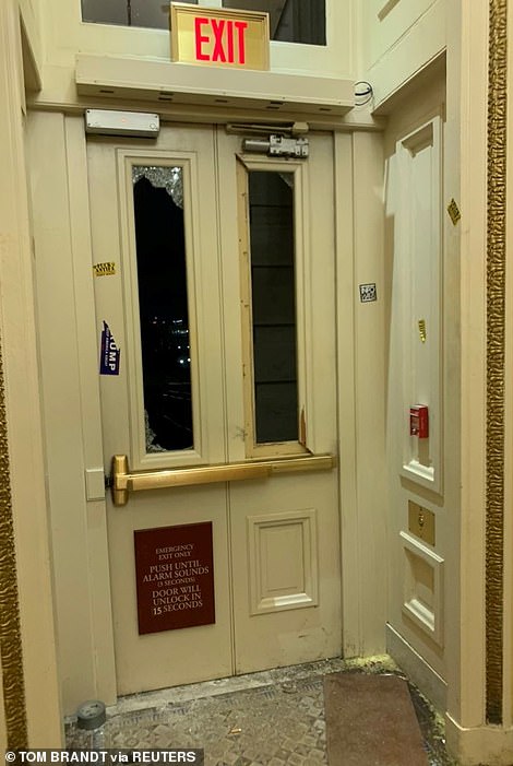 A door with broken windows inside the Capitol and plastered with Trump stickers