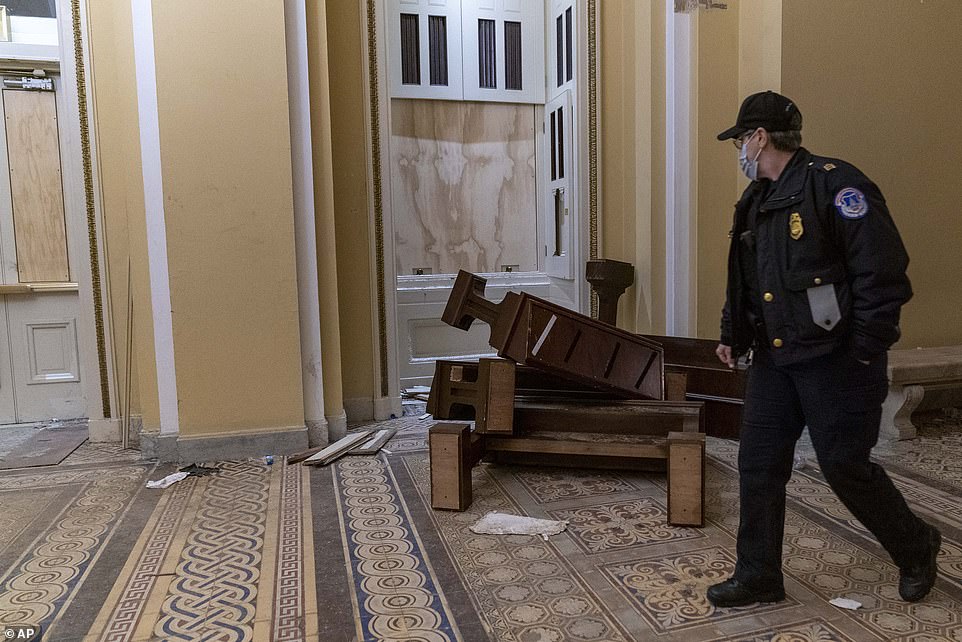 A U.S. Capitol Police officer walks past damage to windows and furniture in the early hours of Thursday as lawmakers continued their debate after the building was secured