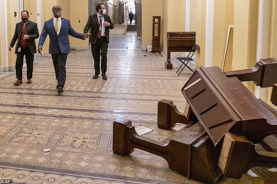Sen. Tim Scott, R-S.C., second from left, walks past damage with staffers in the early morning hours of Thursday