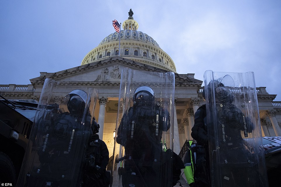 Police stand outside the East Front of the US Capitol at dusk as a curfew begins after pro-Trump protesters stormed the grounds leading to chaos, in Washington, DC