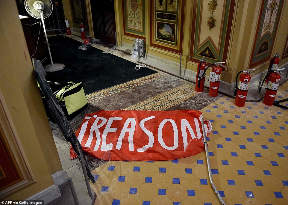 Damage is seen inside the US Capitol building early on Thursday beside dispensed fire extinguishers and a sign which says 'Treason'