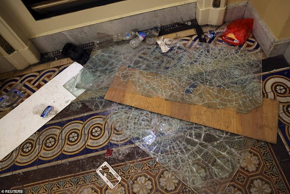 Discarded water bottles and shattered panes of glass are seen in the hallway of the Capitol Building today