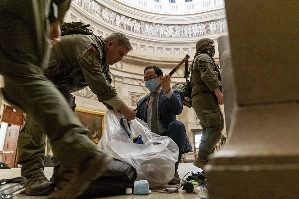 Rep. Andy Kim, D-N.J., helps ATF police officers clean up debris and personal belongings strewn across the floor of the Rotunda in the early morning hours of Thursday