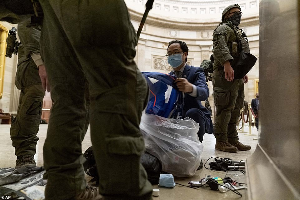 Rep. Andy Kim, D-N.J., helps ATF police officers clean up debris and personal belongings strewn across the floor of the Rotunda in the
 early morning hours of Thursday