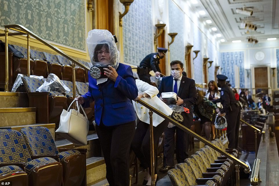 People wearing protective hoods evacuate the House gallery as Trump's mob tries to break into the House Chamber