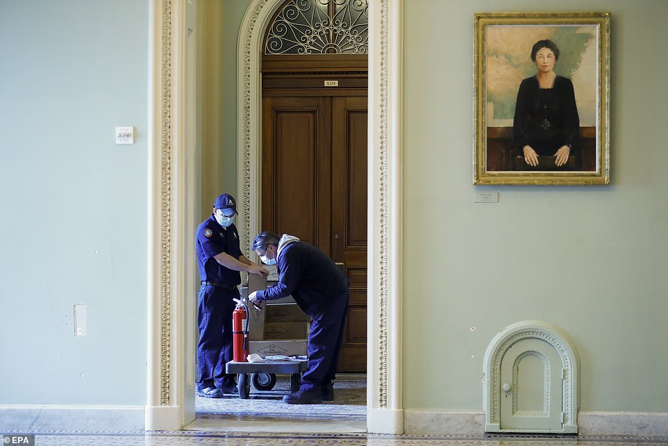 An Architect of the Capitol work crew restocks stolen fire extinguishers near the Senate floor