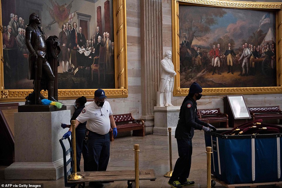 Workers clean the Capitol rotunda, dusting off statues that were vandalized amidst the chaos