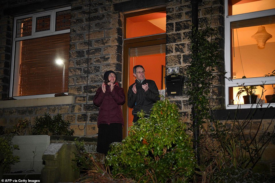 People stand outside their home in Marsden and clap for those helping in the fight against coronavirus after the nation was plunged into a third lockdown