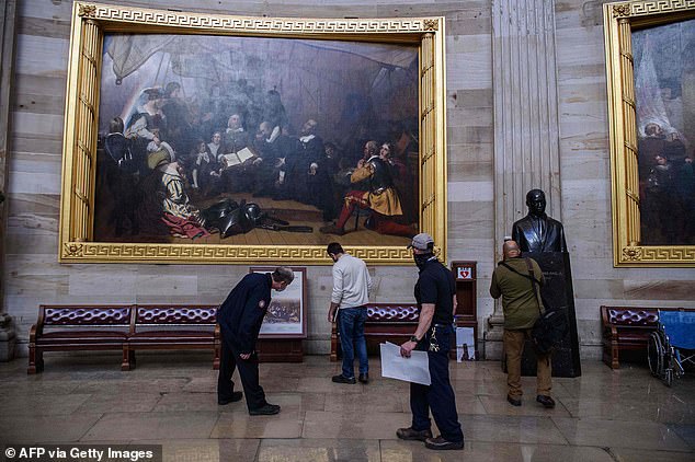 Members of the office of the Architect of the US Capitol are seen checking for damage in the Rotunda in Washington the morning after Trump supporters wreaked havoc