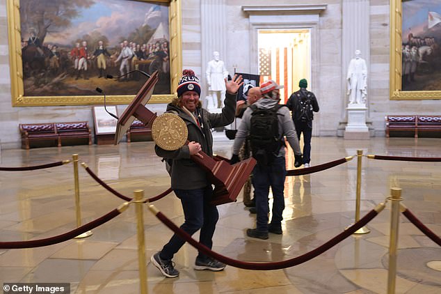 A protester walks through Congress carrying Nancy Pelosi's lectern after storming the Capit
ol