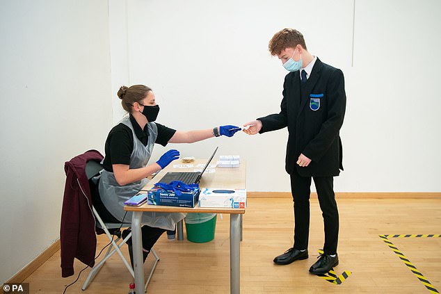 Student Henry Parker receives instructions and equipment on how to take his virus test
