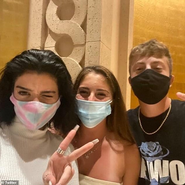 At least they're wearing masks! Dixie, 19, flashed the peace sign while posing with two fans at the resort