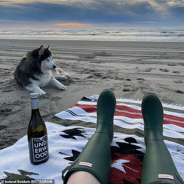 Chilling out: It flashed a cute grin from the back of their pick up truck before finding a spot on the sand next to her while she worked on a bottle of wine