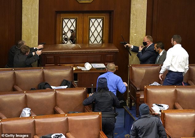 Capitol police officers point their gu
ns at a door that was vandalized in the House Chamber during a joint session of Congress