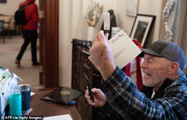 Richard Barnett, 60, shows off a letter from Nancy Pelosi's desk which he stole