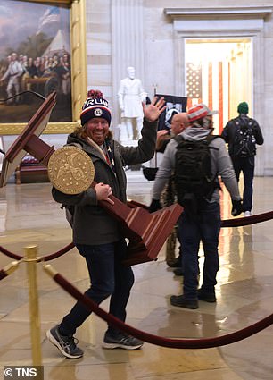 A protester, who has since been identified, is pictured carrying Pelosi's lectern through the Capitol