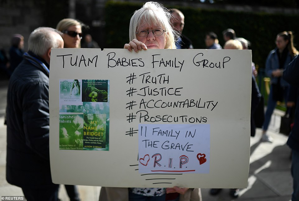 A woman holds a poster at a funeral procession in remembrance of the bodies of the infants discovered in a septic tank, in 2014, at the Tuam Mother and Baby Home, in Dublin, Ireland October 6, 2018