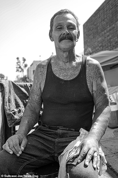 A resident of Skid Row gives a wry smile as he sits for his portrait.