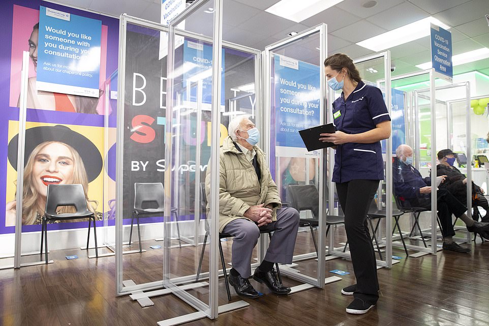 Superdrug nurse Mary Saunders speaks to Henry William Rice, 95, from Guildford as he waits to receive the AstraZeneca Covid vaccine at Superdrug in Guildford