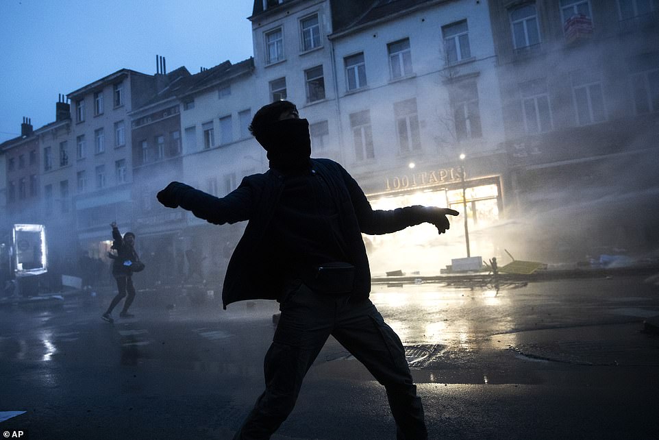 A protester throws stones toward police officers in Brussels on Wednesday as protesters clash with police following the death of a 23-year-old black man in police custody on Saturday
