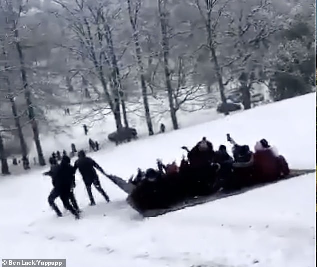 Around 20 people on a makeshift sledge cram onto a tarpaulin at Roudhay Park, Leeds today
