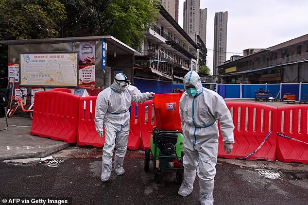 2020: Health workers wearing white hazmat suits work near the Huanan Seafood Wholesale Market in Wuhan which has been linked to the early spread of the coronavirus