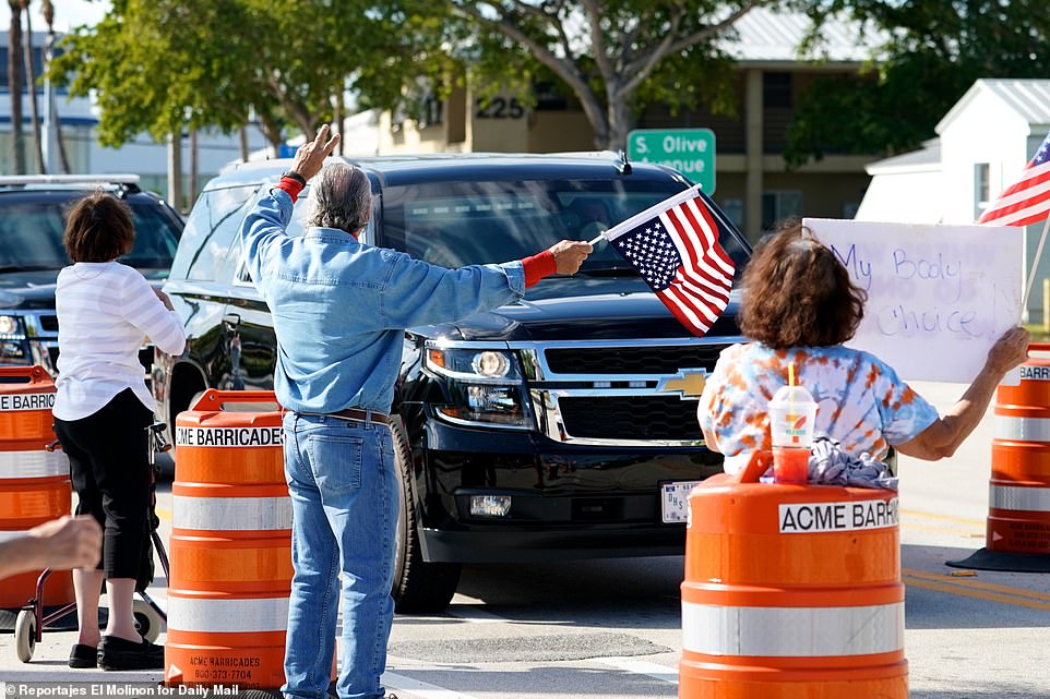 A group of fans stood outside on the road waving American flags as the former commander-in-chief rode by