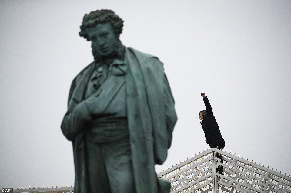 In Moscow, some journalists covering the protests were detained, drawing a rebuke from the U.S. Embassy. Pictured: A man gestures as he climbed up on New Year's decorations next to statue of Alexander Pushkin during a protest against the jailing of opposition leader Alexei Navalny in Moscow
