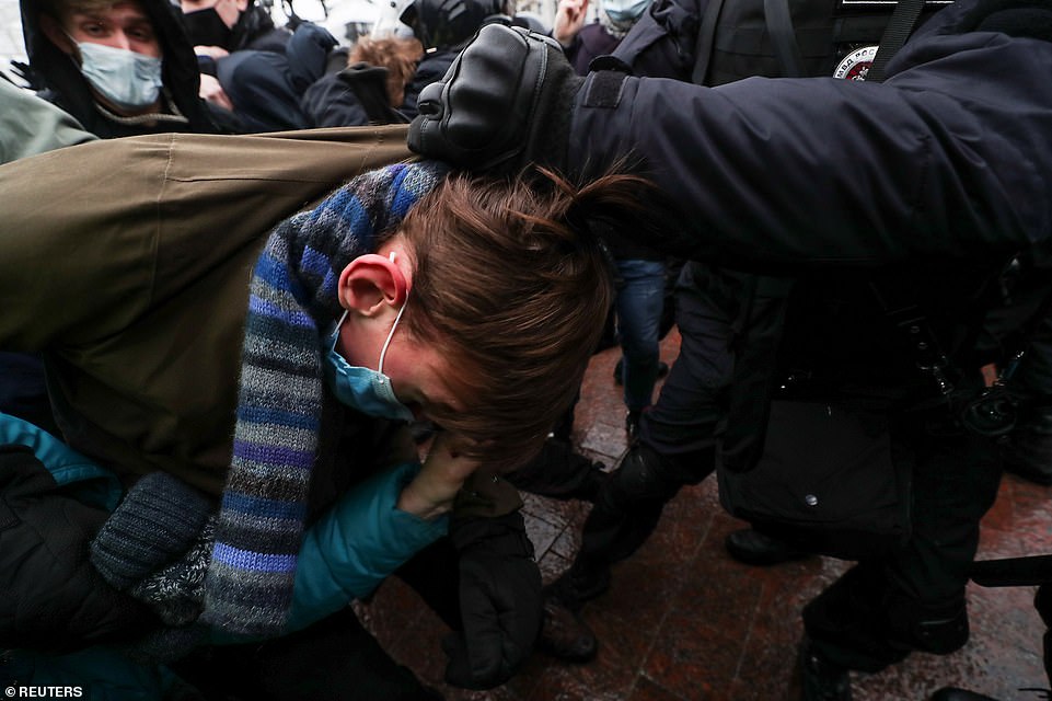 Pictured: A police officers grabs the hair of a protester in Moscow on January 23. Thousands of people gathered in cities across the country including in the Far East on the Pacific coast, Siberia and the Urals, despite police threats to use violence