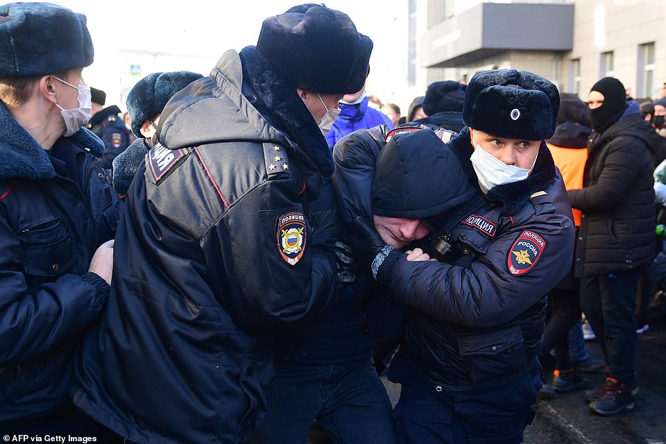 Demonstrators shouted 'Shame, shame' in Pacific capital Vladivostok as heavily armed baton-wielding OMON special forces officers and national guards threw a protester in a police vehicle. Pictured: Officers detain a man during a rally in support of jailed opposition leader