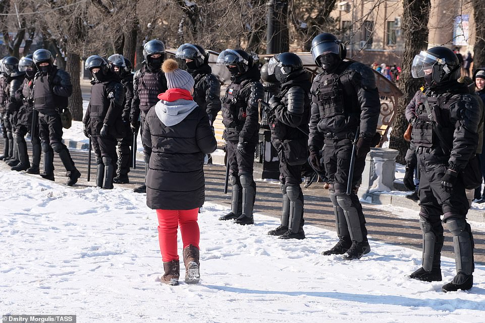 Pictured: A woman walks in front of a row of riot police amid anti-Putin protests on January 23