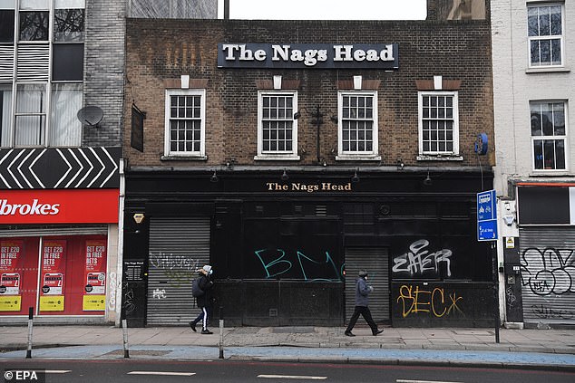 Kate Nicholls, chief executive of the UK Hospitality trade body, said many pubs and restaurants would 'struggle to survive' if they were forced to keep their doors closed until May. Pictured: A man walks past a closed pub in east London