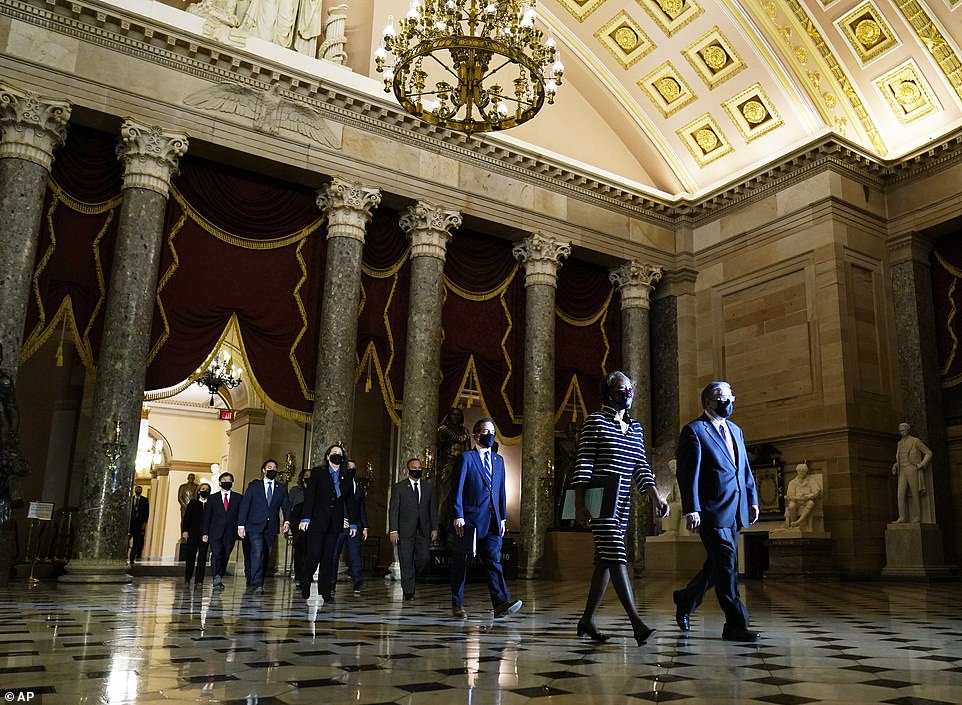 Article on its way: Clerk of the House Cheryl Johnson along with acting House Sergeant-at-Arms Tim Blodgett, lead the Democratic House impeachment managers as they walk through Statuary Hall on the way to the Senate