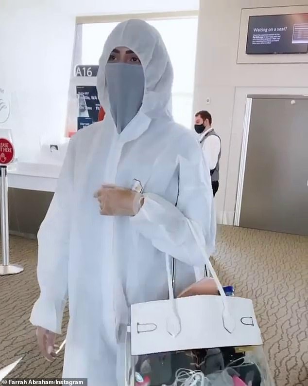 Extreme measures: The one-time Penthouse book critic suited up in a white hazmat-style outfit as she boarded a plane to Alaska and showed herself sanitizing her seats video screen