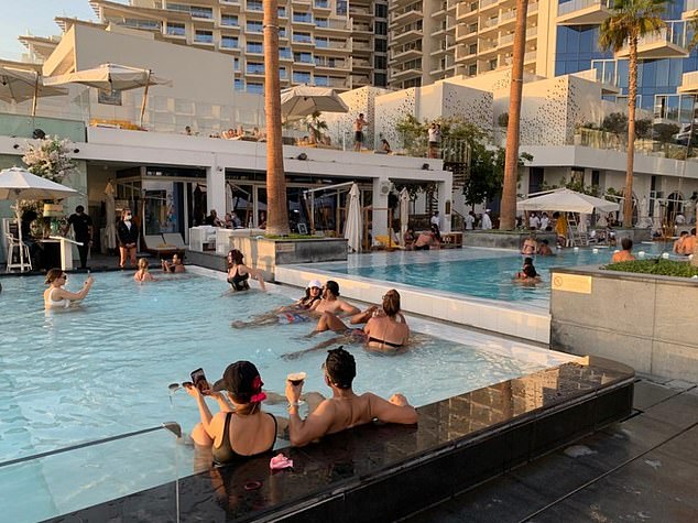 People enjoy sitting in a swimming pool in Dubai yesterday as UK brought in a travel ban for the United Arab Emirates