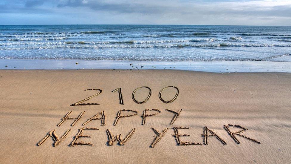 Happy New Year 2100 written in the sand.
