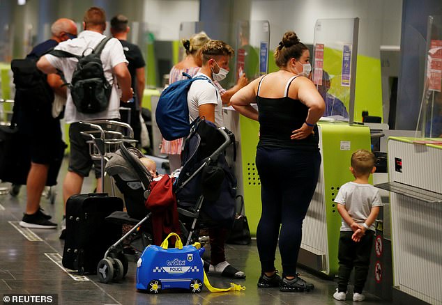 Airlines of America has urged the Trump administration to lift travel bans on passengers coming to the US in lieu of a negative coronavirus test before take-off (pictured: British tourists returning to UK check in their luggage in Spain)