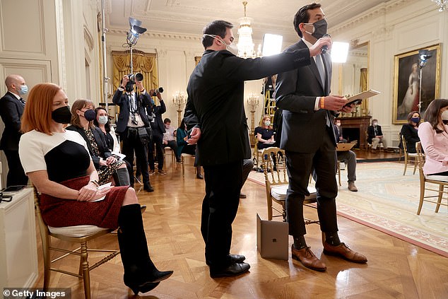A White House staffer holds up a microphone for Associated Press reporter Zeke Miller to ask a question to President Biden as White House press secretary Jen Psaki looks on