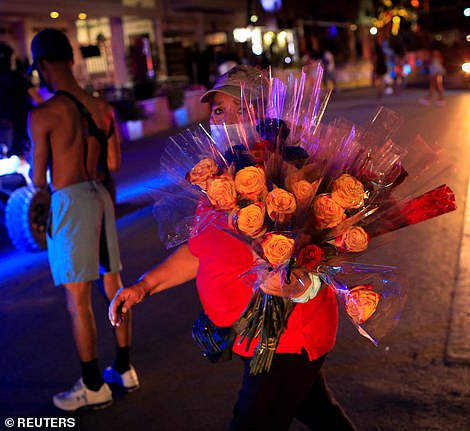 A street vendor walks away as police officers ask revelers to leave during an 8pm curfew imposed by local authorities