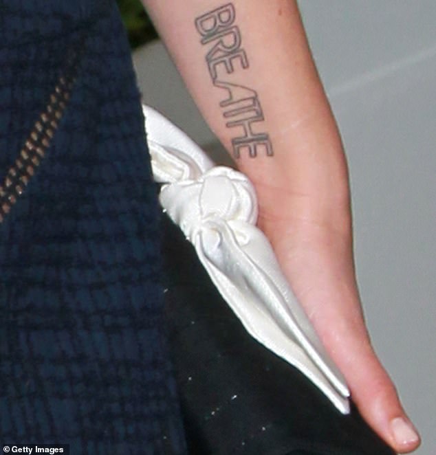 Statement: Her various pieces of body art include a cherub holding a banner at her lower back as well as 'BREATHE' written across her left forearm