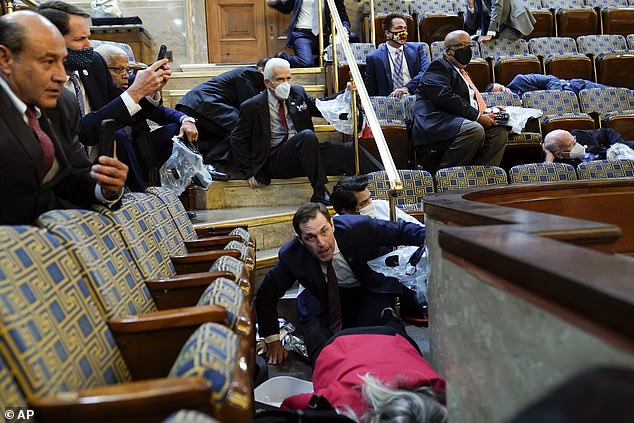 People shelter in the House gallery as rioters break into the House Chamber at the Capitol on January 6