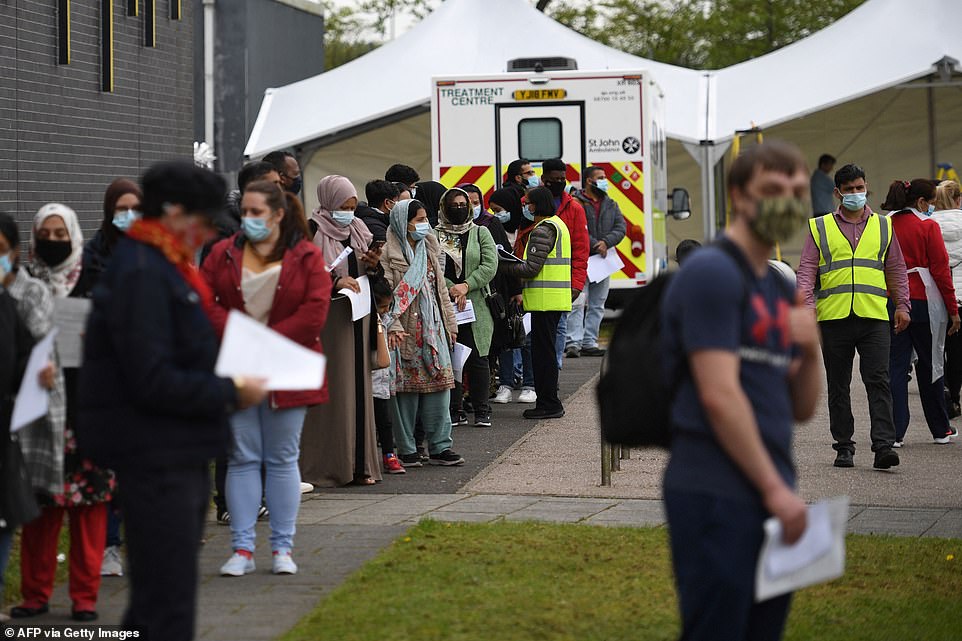 Members of the public queue at a temporary Covid-19 vaccination centre at the Essa academy in Bolton on Friday