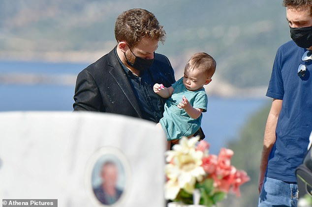 Widower Babis pictured with his 11-month-old daughter at the burial of Caroline on the island of Alonnisos