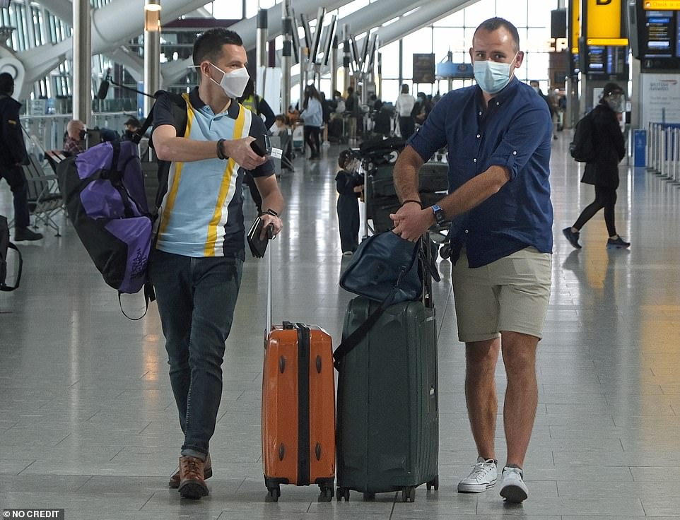 Two passengers wearing face masks wheel their suitcases through Heathrow's Terminal 5 as the global travel ban is eased