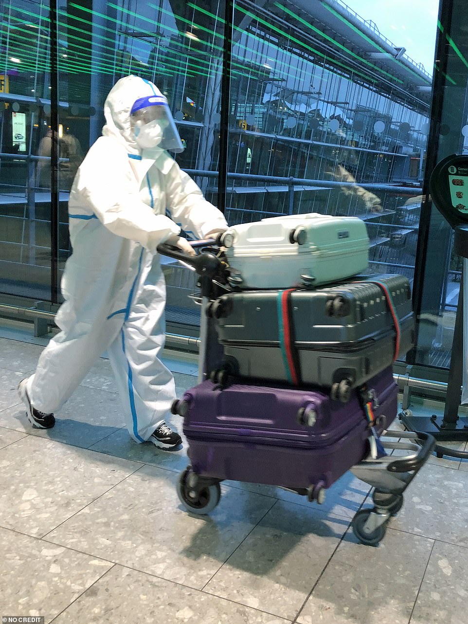 A passenger in a hazmat suit is seen in Heathrow Airport Terminal 5 this morning as covid restrictions ease today