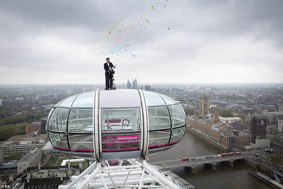 Sunny Jouhal, general manager of the lastminute.com London Eye, stands on top of a London Eye pod to celebrate the re-opening of the attraction today