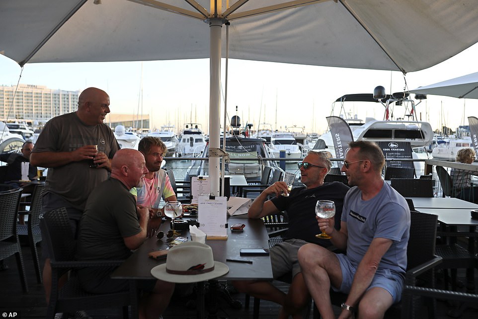 A group of tourists who flew in earlier in the day from Manchester and Essex enjoy a drink by the marina in Vilamoura, in Portugal's southern Algarve region